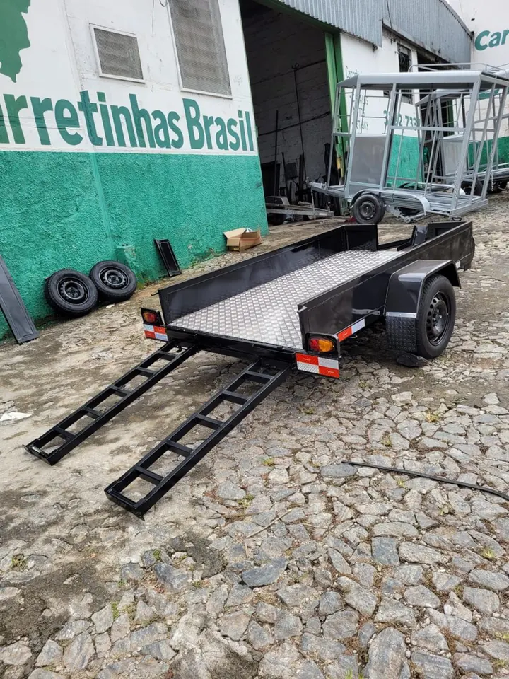 Carretinha para quadriciclo com as rampas de embarque abaixadas, em frente à fábrica